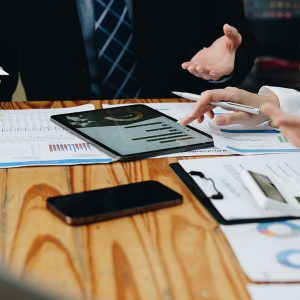 Close up diverse colleagues working on project together, sitting at table in boardroom, working with legal documents, financial report with statistics, employees engaged in teamwork at corporate meeting.