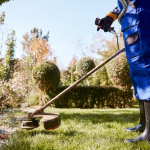 gardener-with-weedwacker-cutting-grass-garden