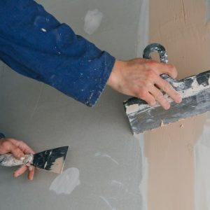 plasterer-man-works-plastering-two-trowels-plasterboard-blue-uniform